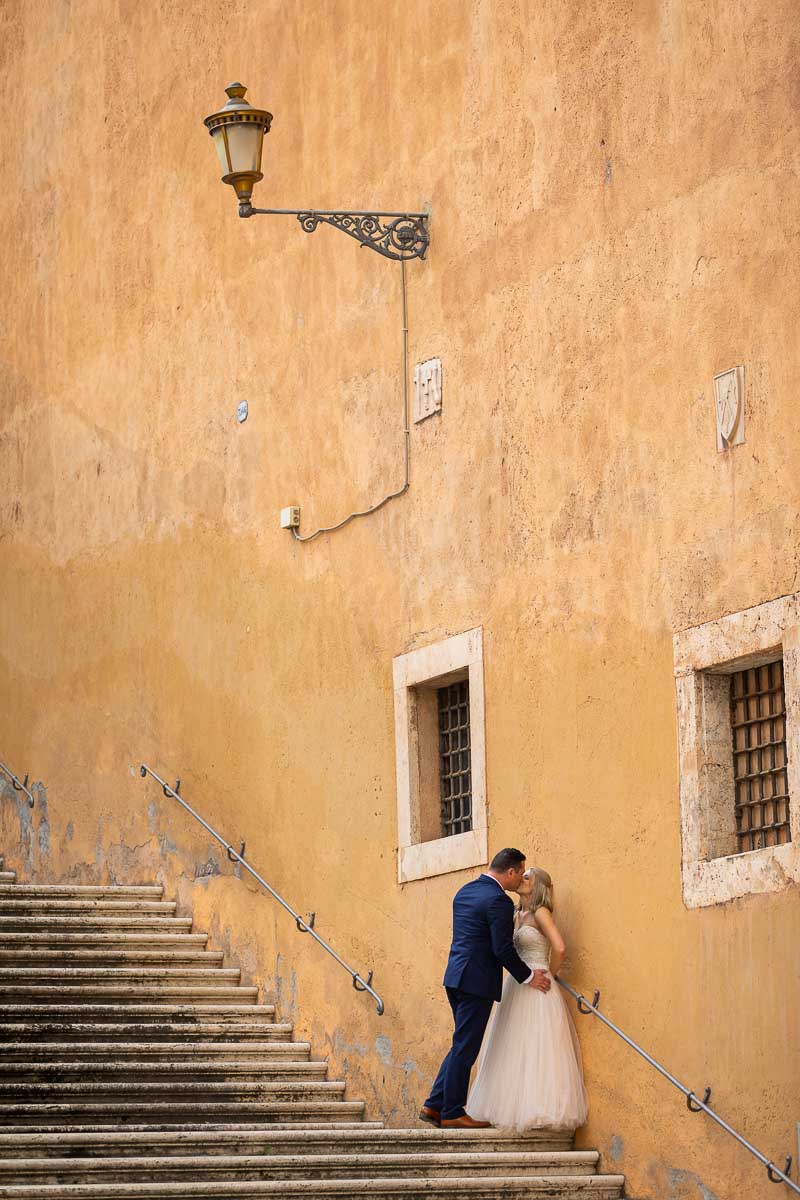 Portrait picture of the newlywed couple on a large set of stairs under roman light post