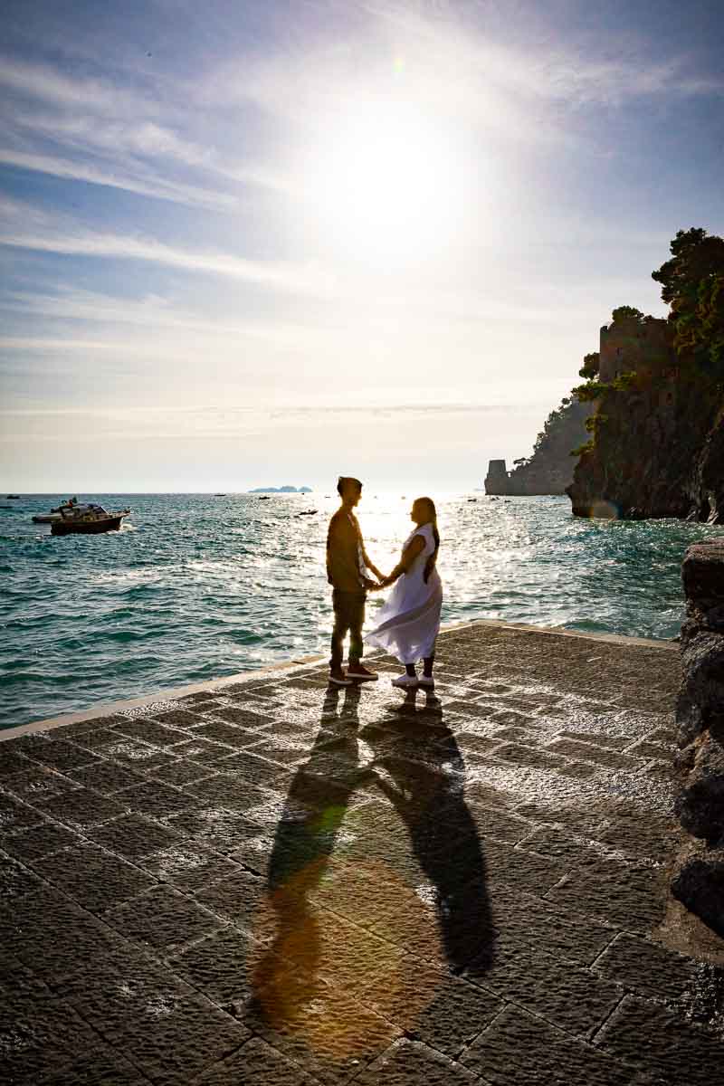 Silhouette picture holding hands together at the seaside port shooting against sunlight