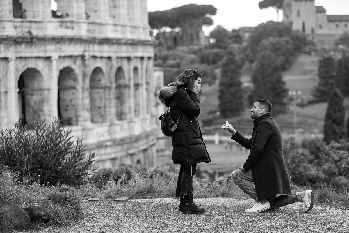 Knee down surprise wedding proposal photographed at the Roman Coliseum with black and white image processing