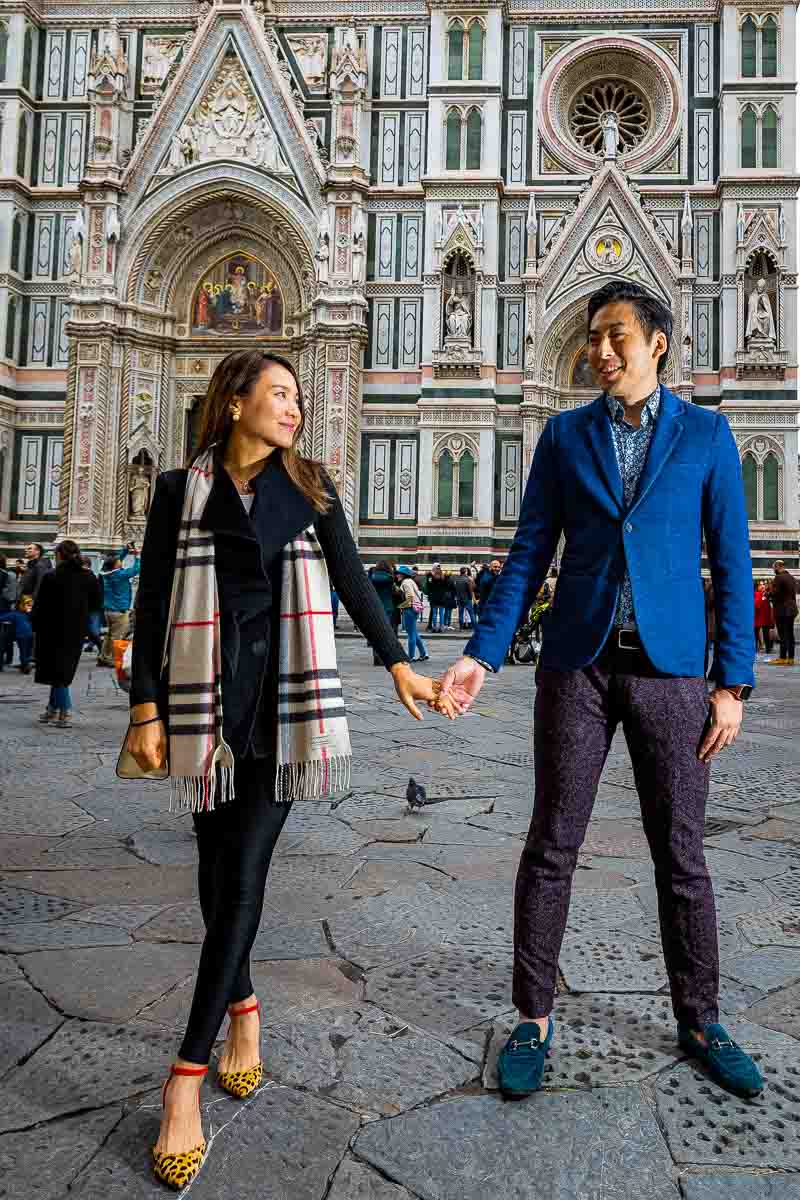 Couple standing and holding hands in front of Cathedral of Santa Maria del Fiore in Florence Italy