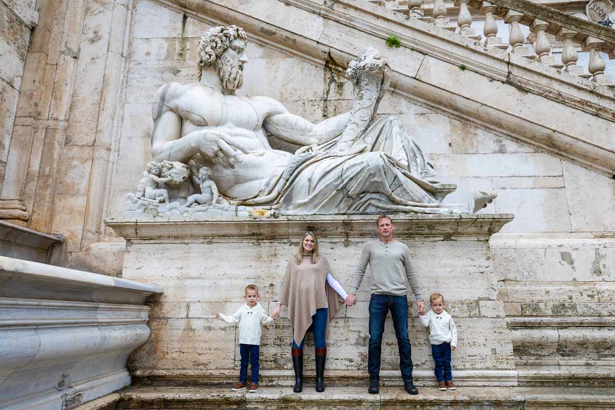 Family Photographer Rome. Picture taken underneath an ancient marble roman statue in the heart of the city in Piazza del Campidoglio