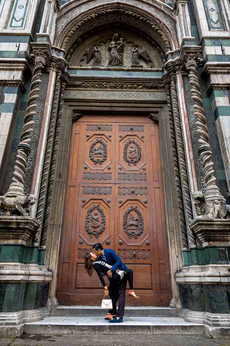 Engagement photo session posing a dip right in front of a large massive wooden door side entrance to the Duomo Cathedral