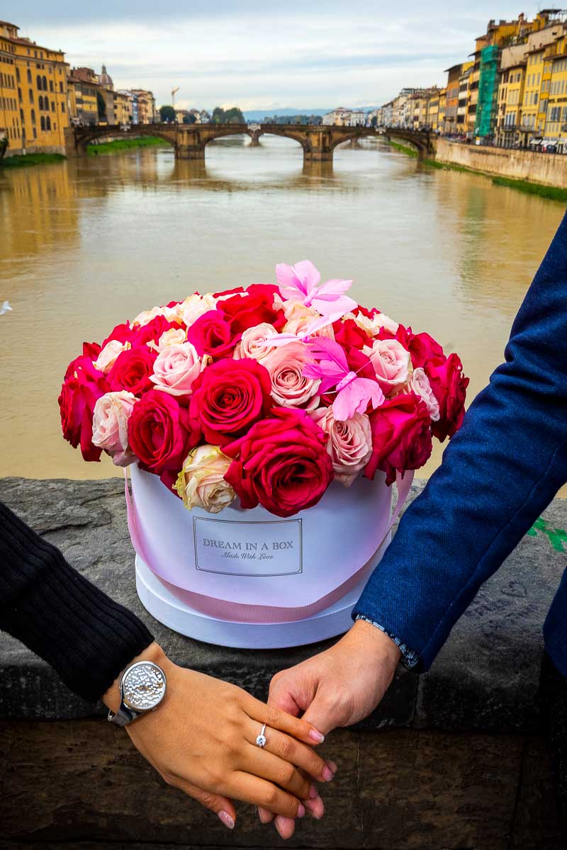 Engagement ring photo taken in Florence on Ponte vecchio over the Arno river with a beautiful bouquet of red roses in a box