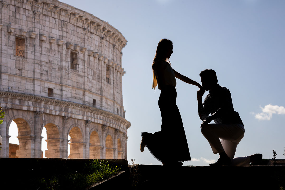 Silhouette photo of a couple kissing hand. Chivalry gesture in Rome's Coliseum