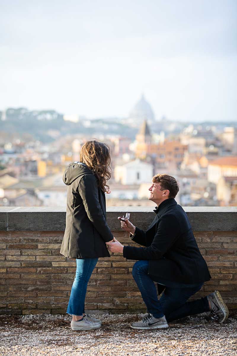 Knee down surprise wedding proposal candidly photographed on top of the Aventine hill in Rome Italy by the Giardino degli Aranci park