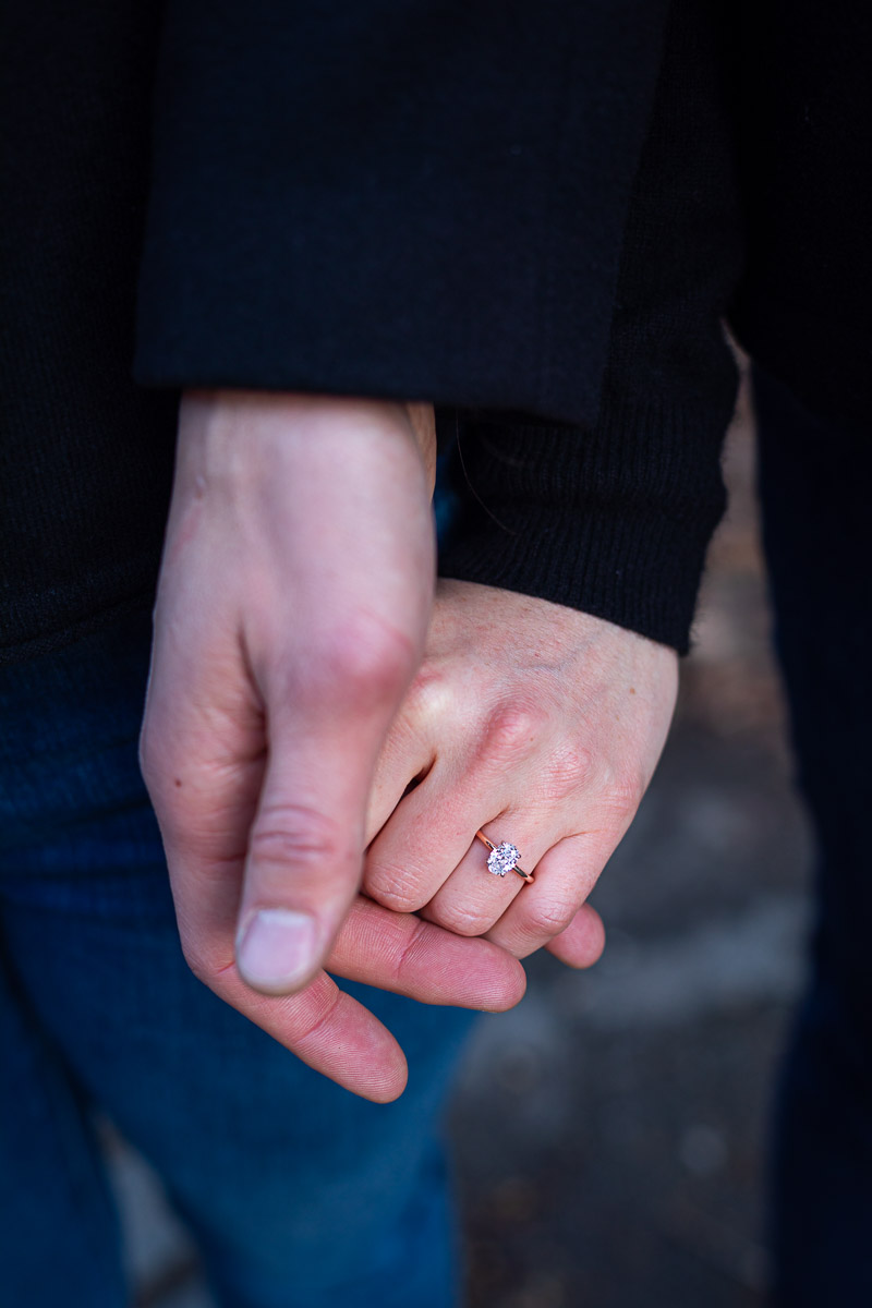 Close up image of the engagement ring holding hands 