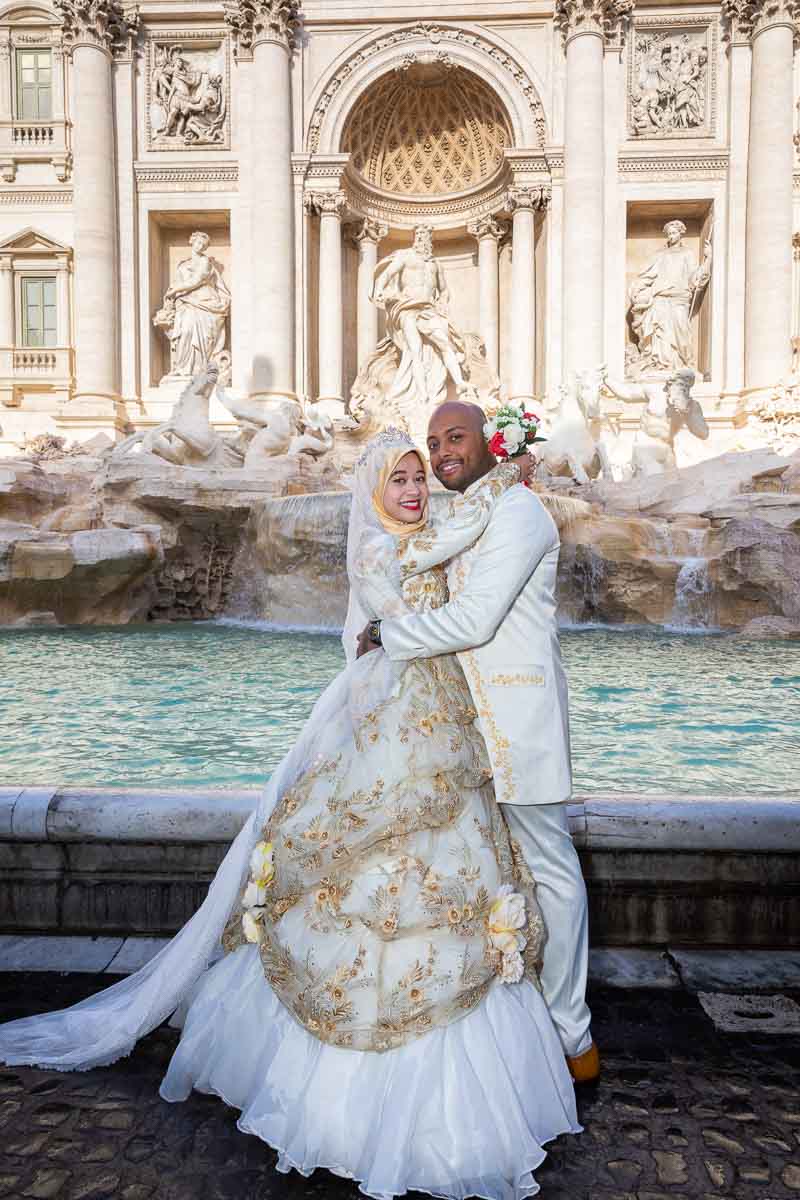 Bride and groom taking pictures together posed in the front part of the Trevi fountain. Wedding PhotoShoot in Rome