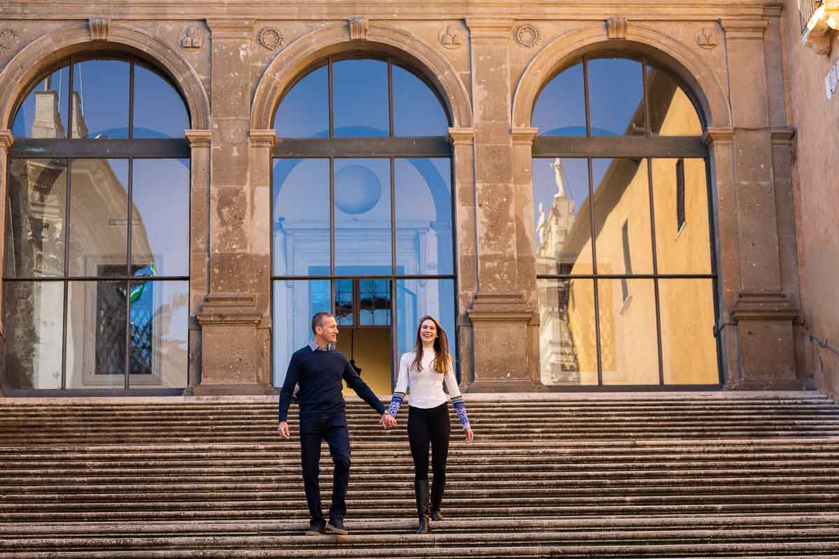 Walking down a large staircase hand in hand with the city of Rome reflected in the windows