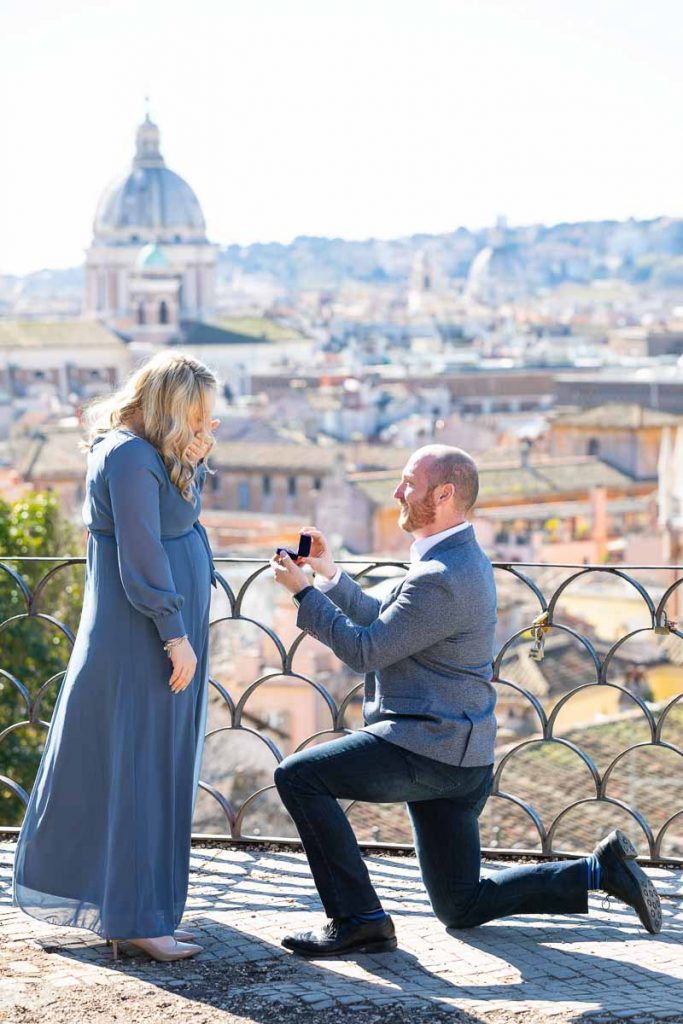 Man kneeling down for a romantic wedding marriage proposal overlooking the stunning city of Rome from the above Pincio terrace outlook