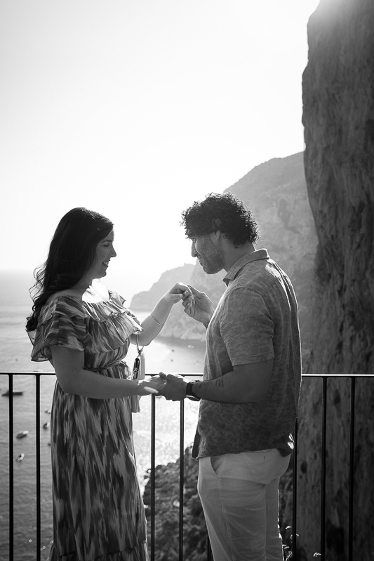 Chivalry moment photographed in black and white with beautiful seaside views. Capri surprise proposal. Black and white photography 