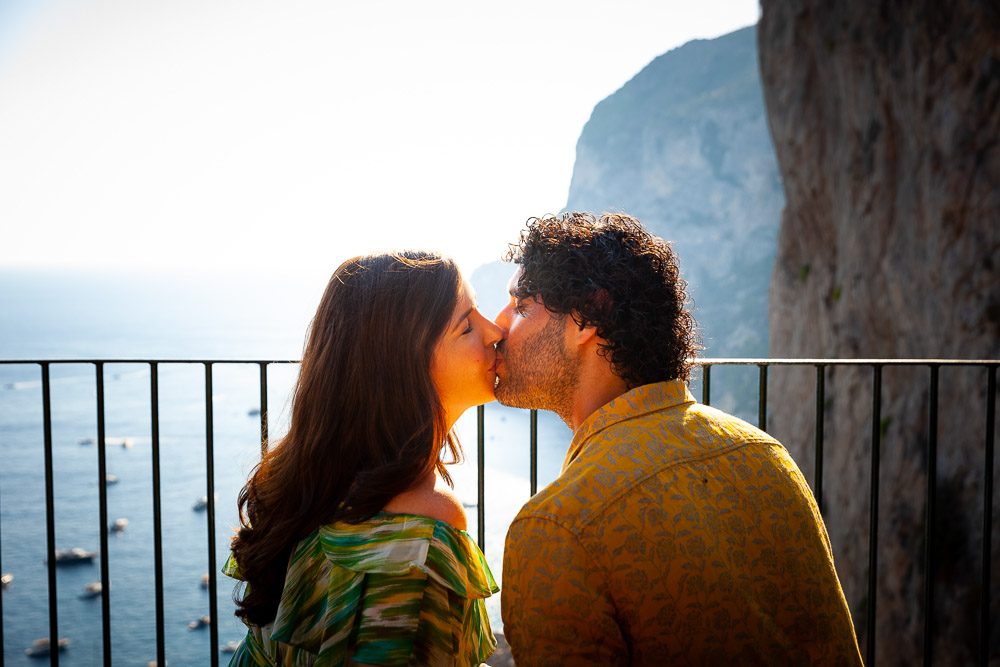 Engagement couple kissing in color photography during a beautiful sunset over the waterfront