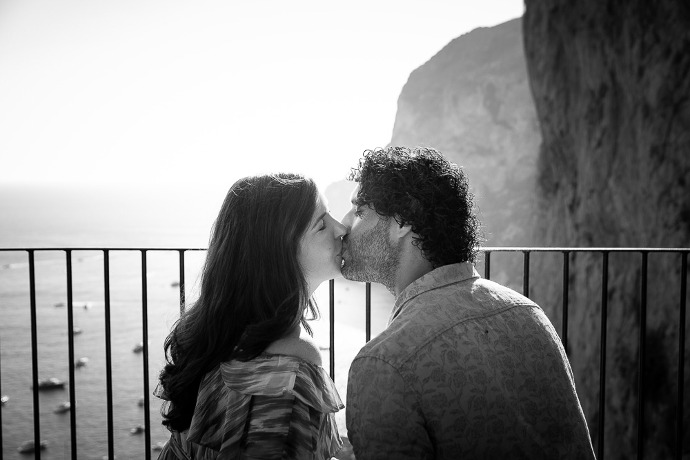 Couple kissing at sunset before an amazing view of the Italian sea. Image in black and white