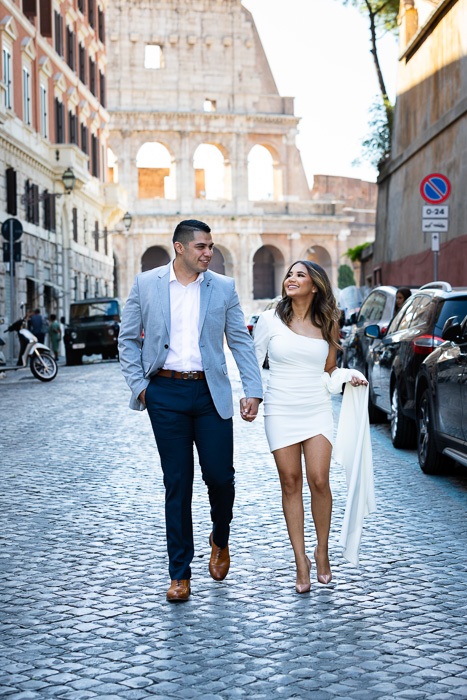 Couple walking on cobblestone alleyways in the streets of Rome with the Roman Colosseum as unique backdrop