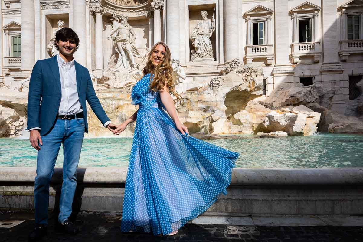 Taking holding hands pictures at the Trevi fountain wearing the blue dress