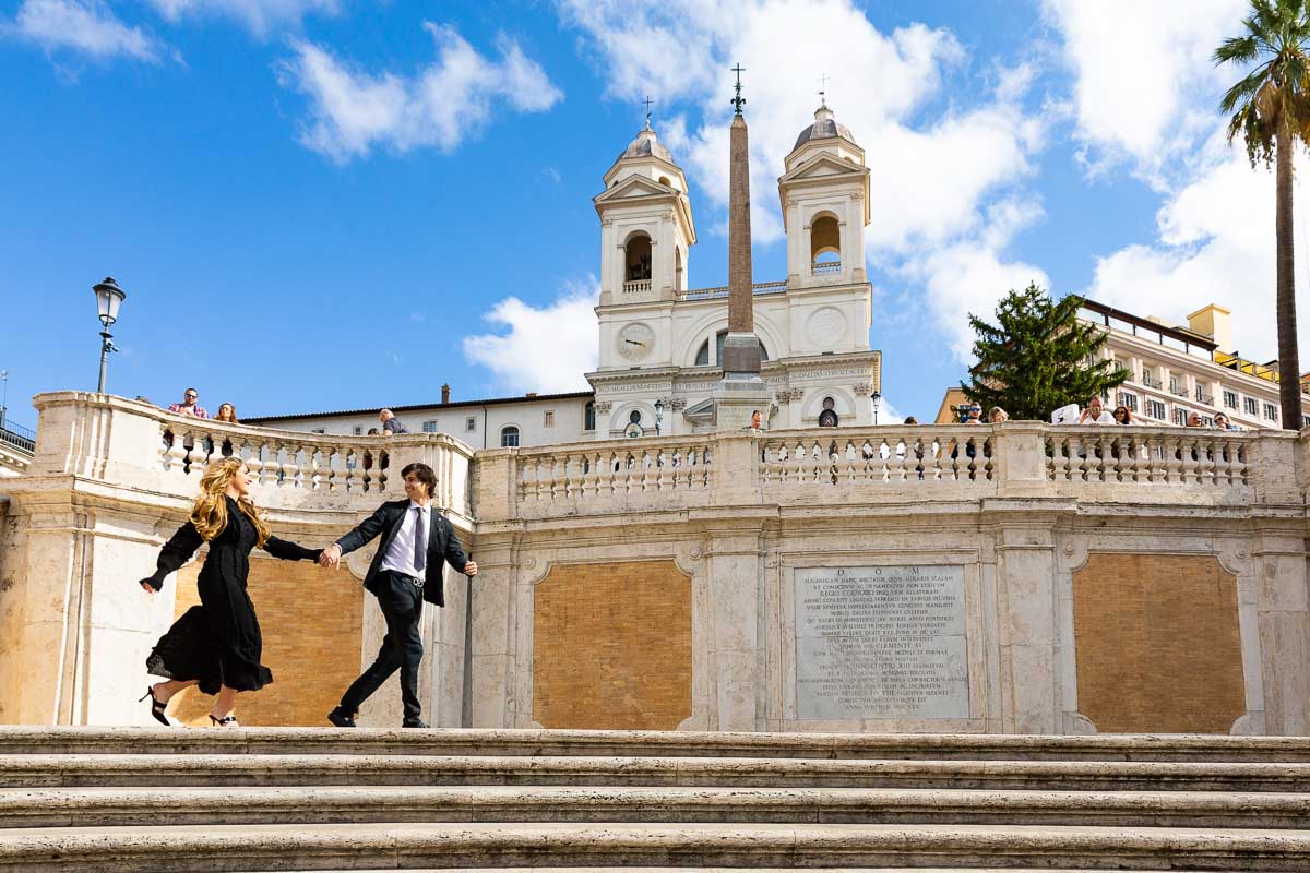 Couple running from one end of the square to the next in Piazza di Spagna in Italy