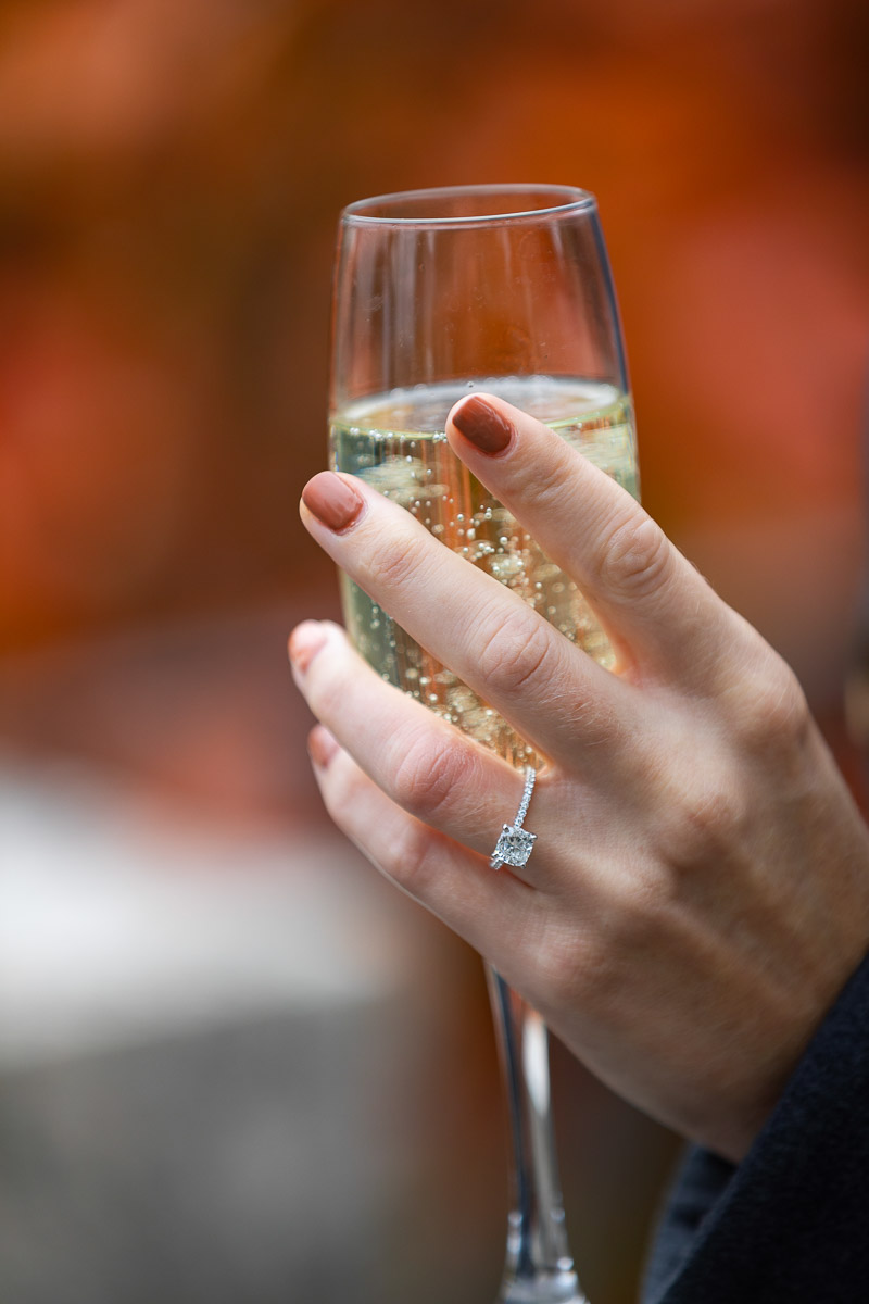 Diamond engagement ring on hand while holding a prosecco glass
