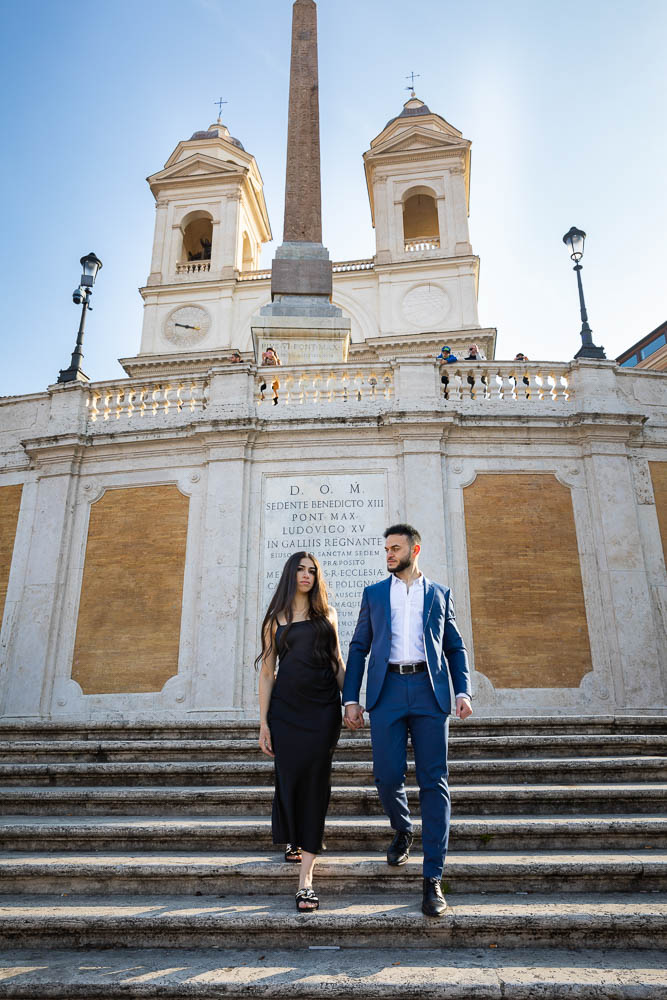 Couple holding hand and walking down the Spanish steps during an engagement photo shoot in Rome Italy