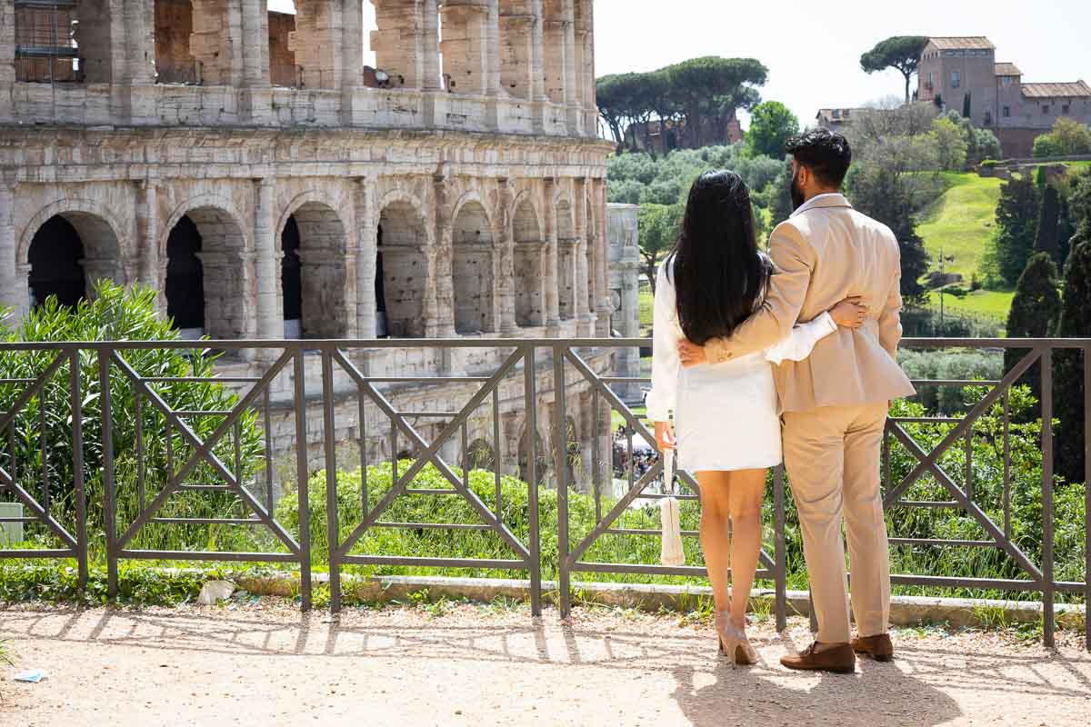 Couple together in Rome dressed in formal attire looking at the Colosseum scenery during a roman photoshoot at the Colosseum