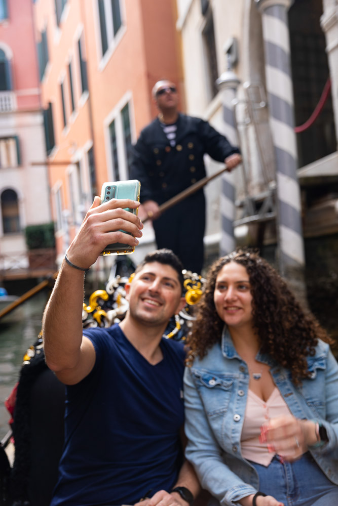 Taking a selfie picture together with a gondoliere in the background