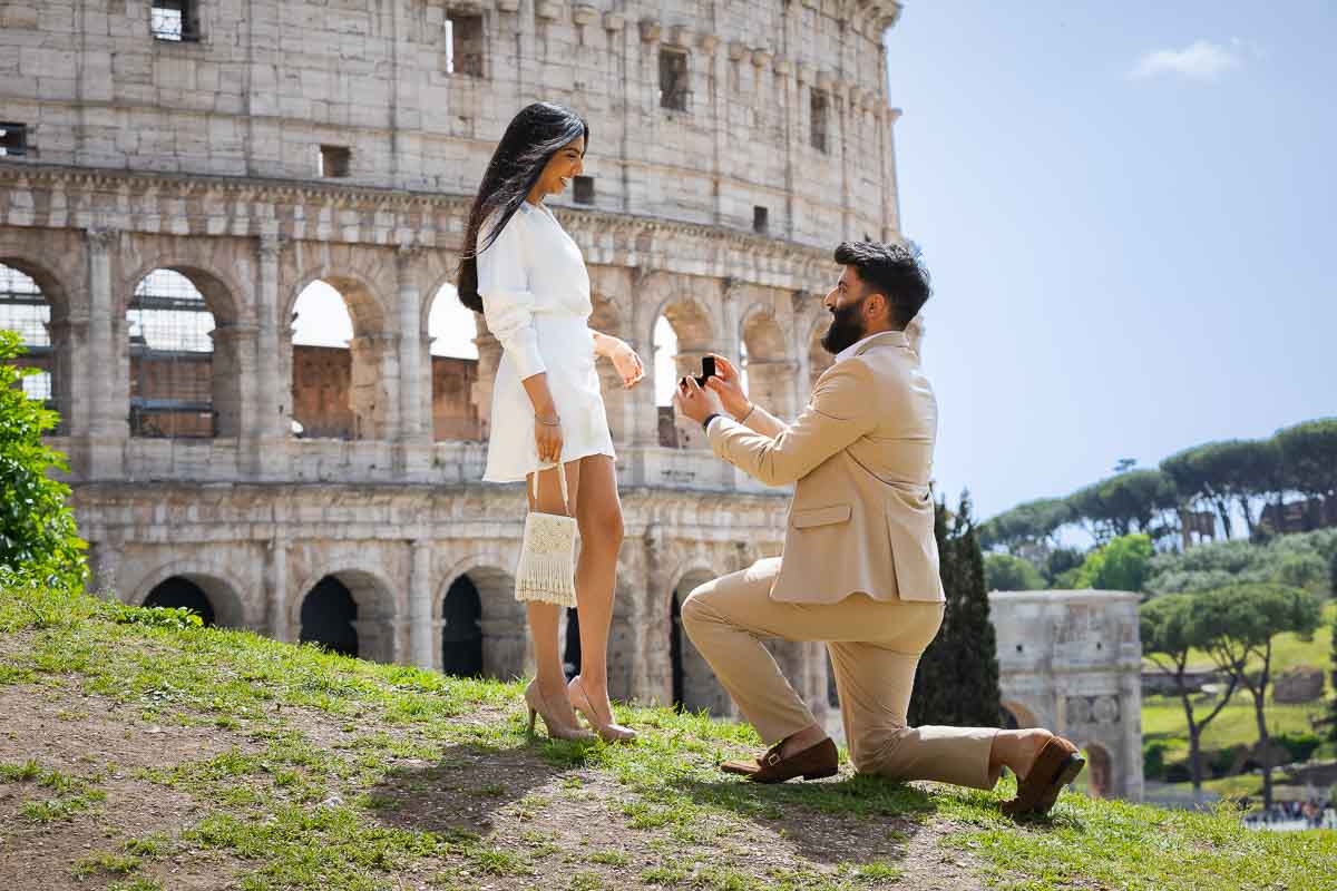 Color photography version of a surprise wedding proposal candidly photographed at the Roman Coliseum during an engagement photo session in Rome