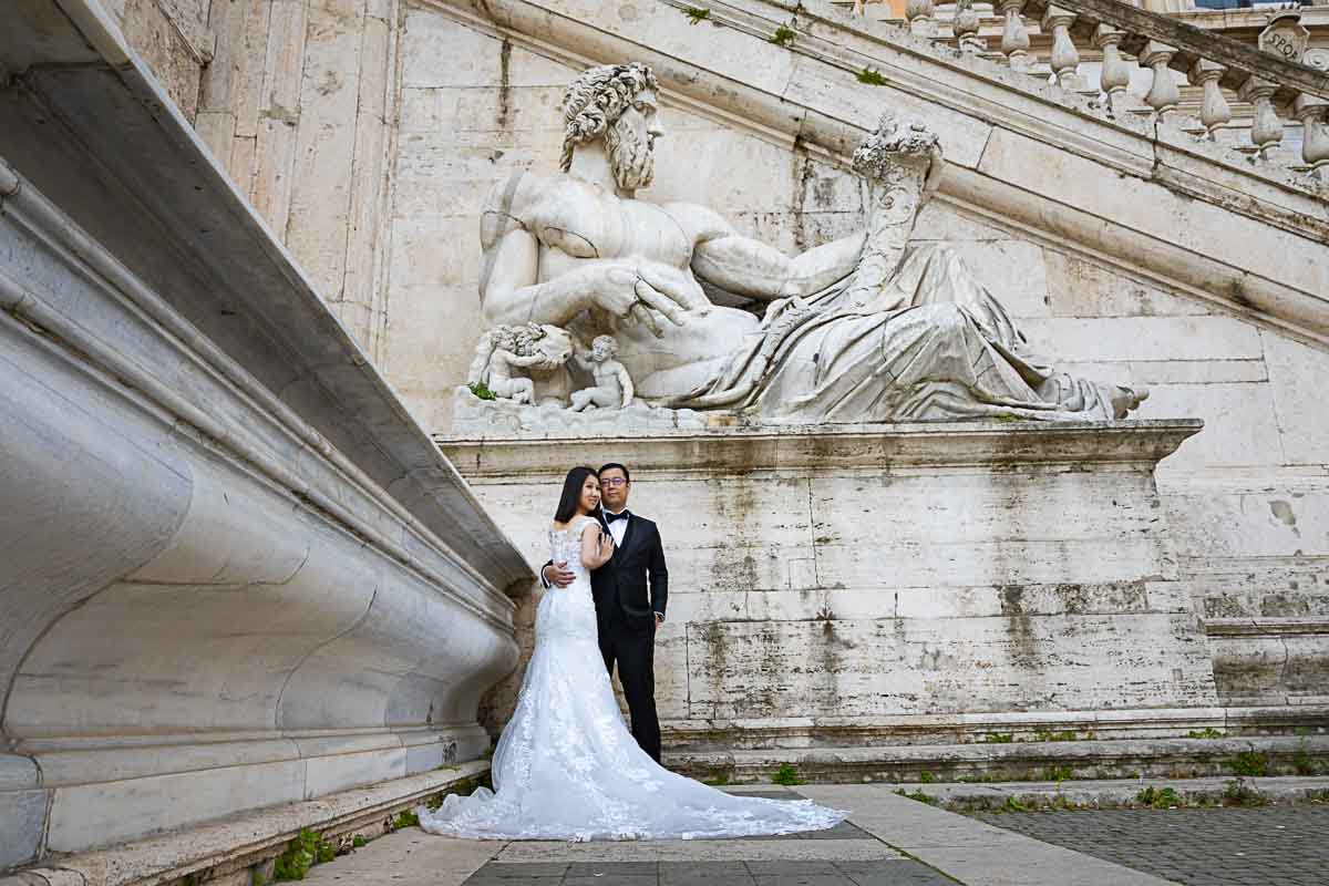 Classic portrait image in wedding attive taken under a large marble statue playing with photographic geometries