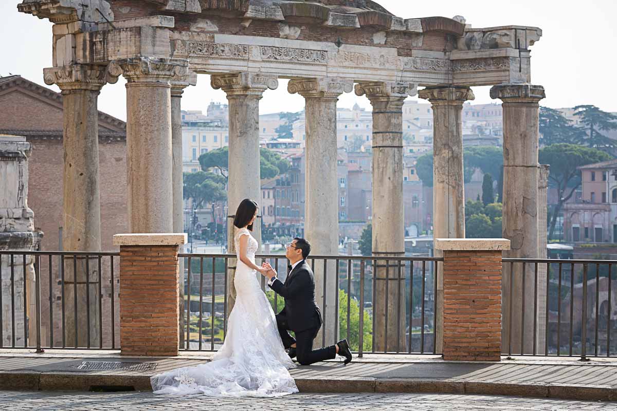 Knee down wedding proposal at the roman forum with ancient temples and ruins in the background 