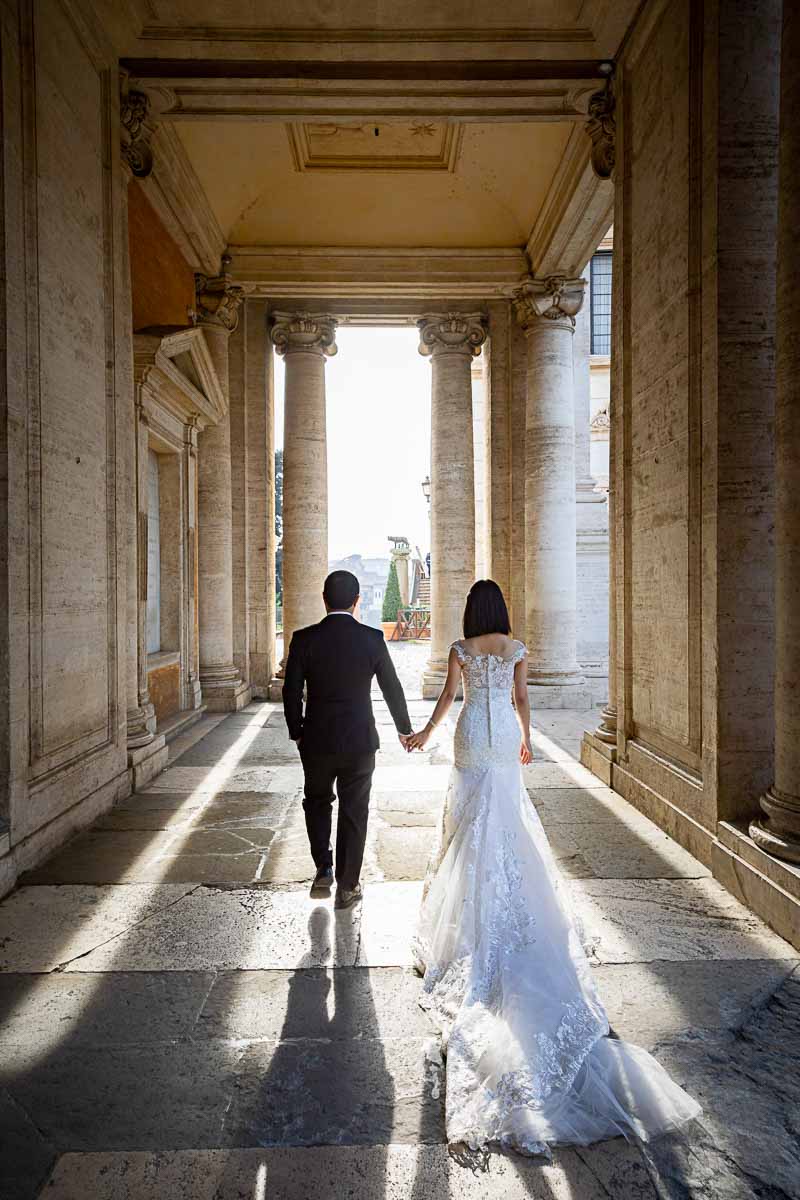 Sposi Novelli walking hand in hand against the sun in the ancient city of Rome