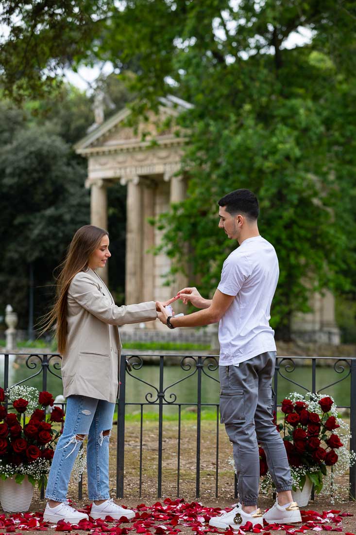 Just engaged in Rome Italy by a lake with a view. Photographing the moment in which the engagement ring is being out on