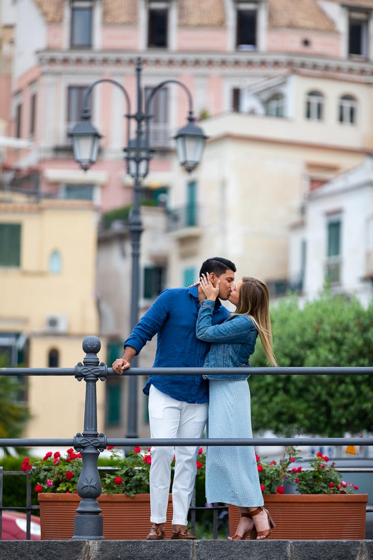 Kissing in the town of Amalfi while standing behind a railing