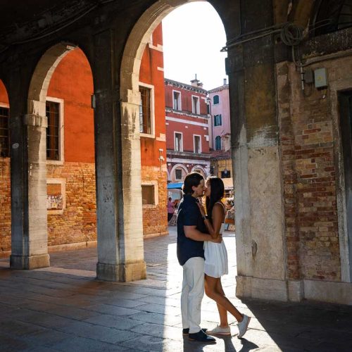 Couple posed underneath porticos during a photoshoot in Venice Italy