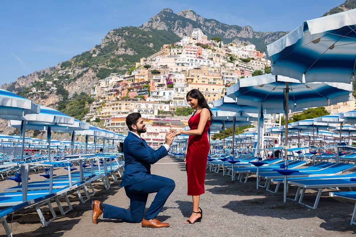 Positano Wedding Proposal candidly photographed on the beach with colorful sun umbrellas all around 