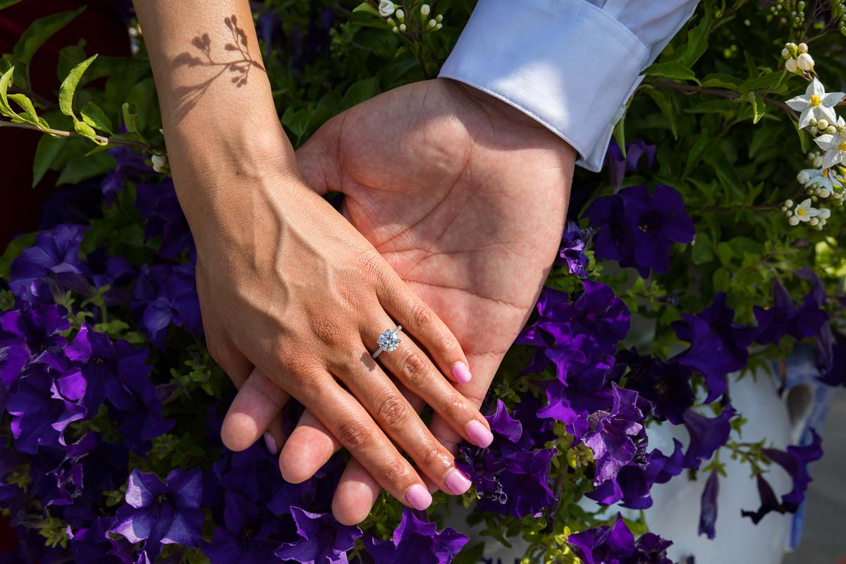 Holding hands together wearing the new engagement ring photographed over beautiful purple flowers. Wedding proposal in Positano 