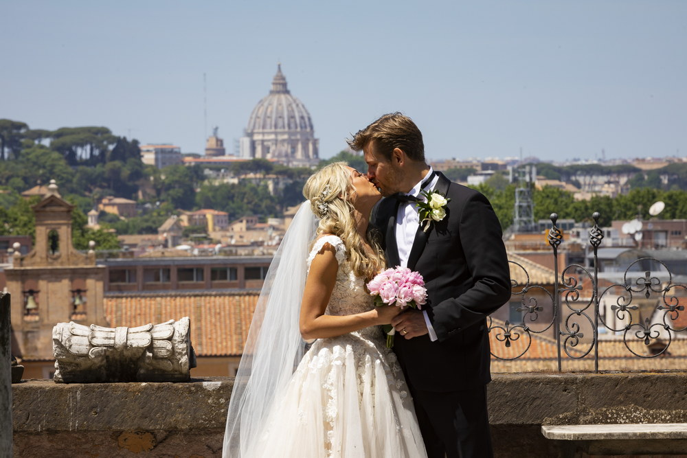 Kissing the beautiful bride with the view of ancient Rome's Vatican in the far distance