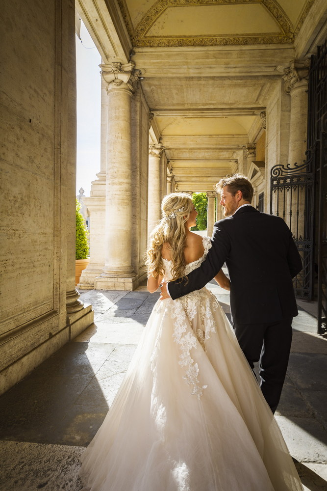 Just married couple taking pictures under the Rome's porticos found in Campidoglio square