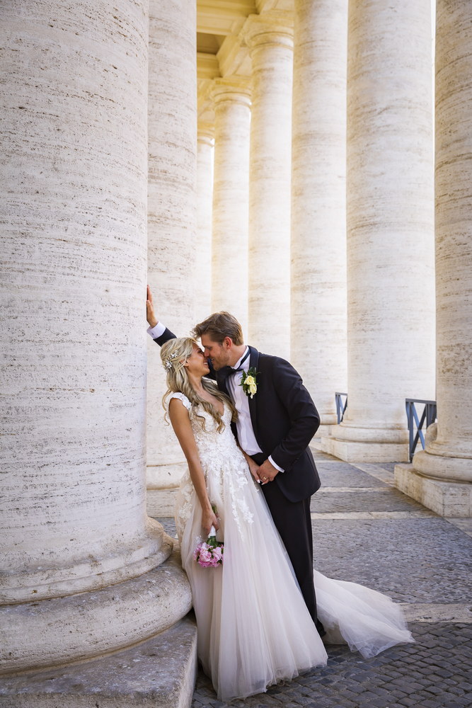 Portrait picture of the bride and groom under the colonnade of Saint Peter's square in the Vatican. Rome. Italy