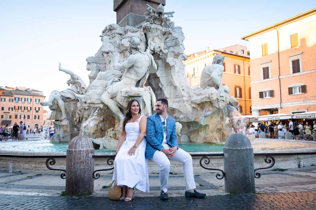 Posed portrait sitting down on the edge of the fountain of the four rivers found in the center of Piazza Navona