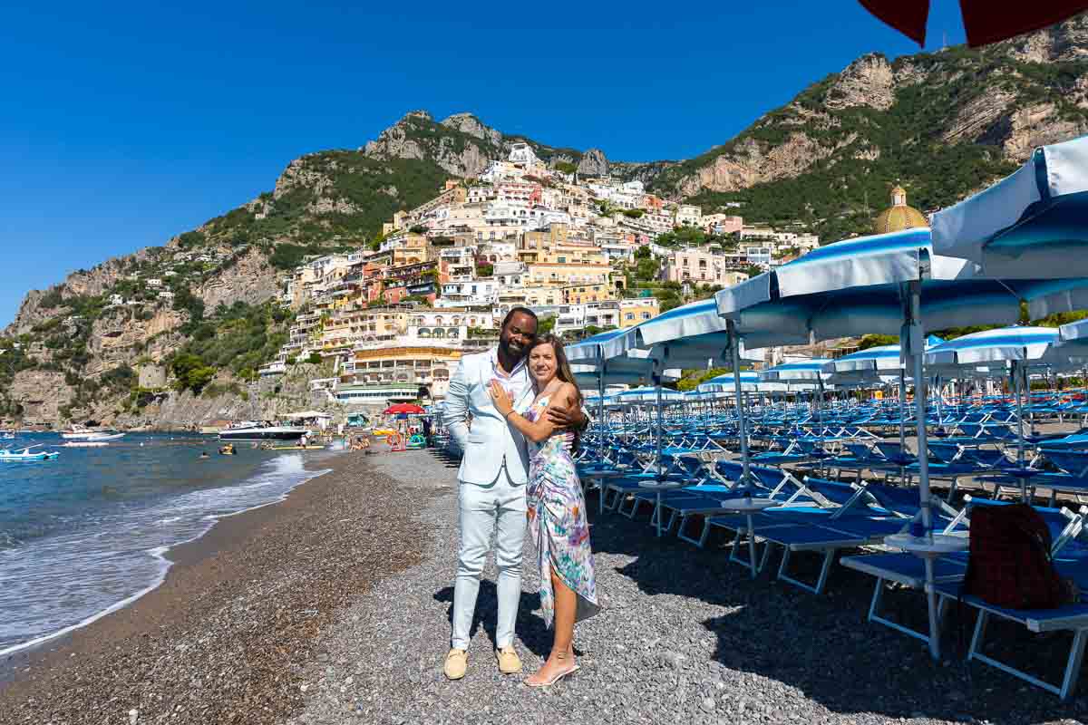 Oceanside just engaged couple portrait by a blue beach resort with the town in the far distance