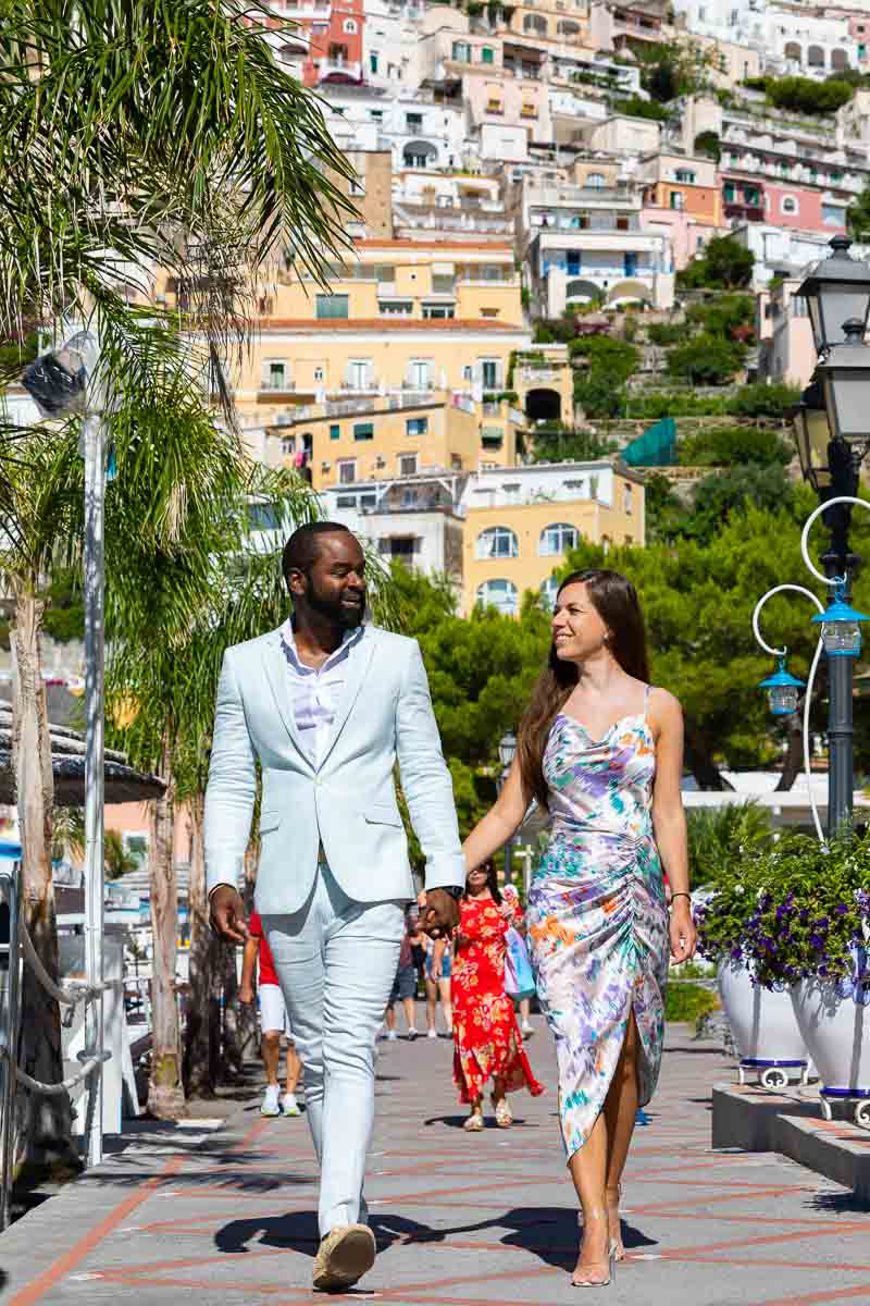 Walking hand in hand on Positano's beach boardwalk that leads to the sea 