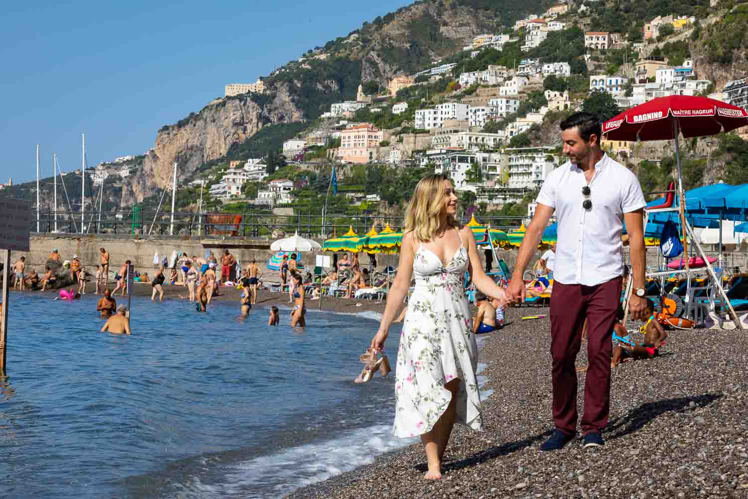 Walking on the beach holding hand and holding shoes 