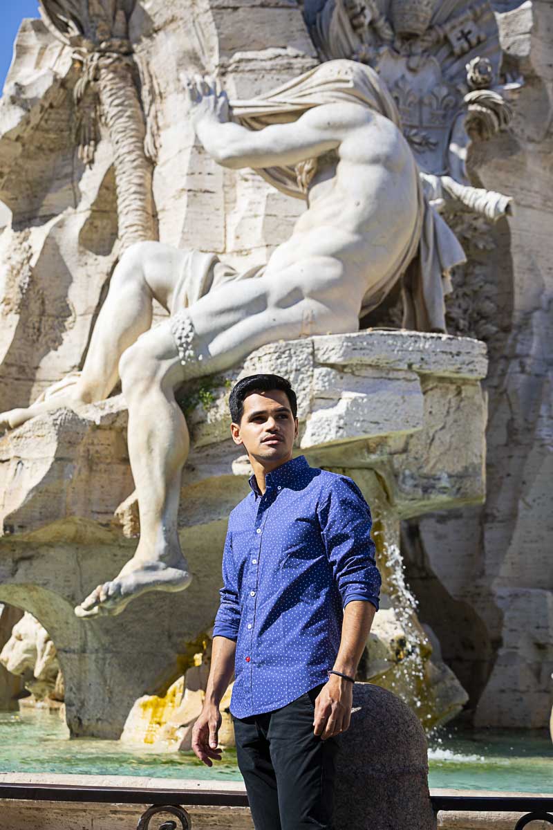 Looking sideways. Posing under a statue found on the fountain of the four rivers in Rome Italy