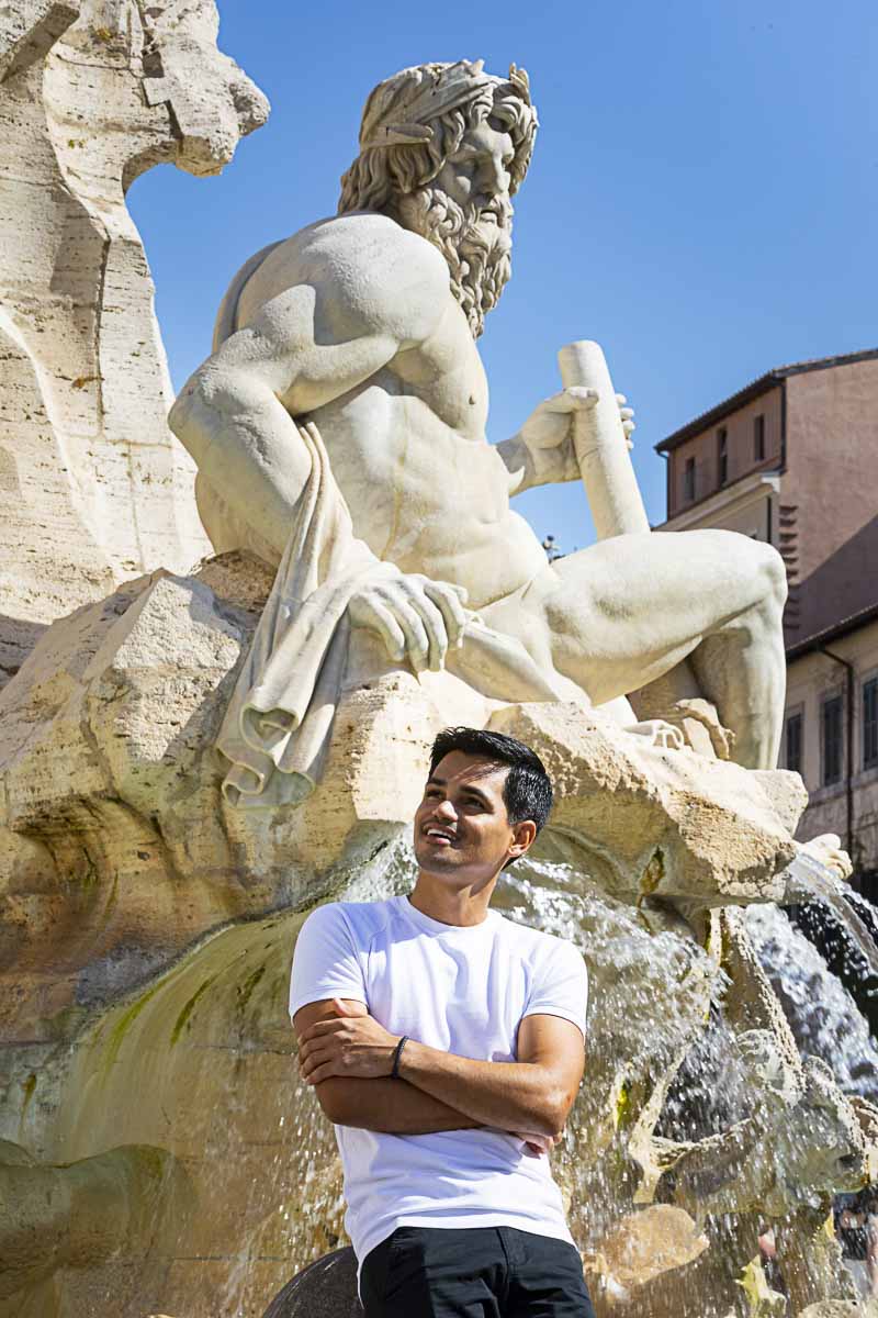 Male model posed portrait standing in front of the Fontana dei Fiumi in Piazza Navona a Roma