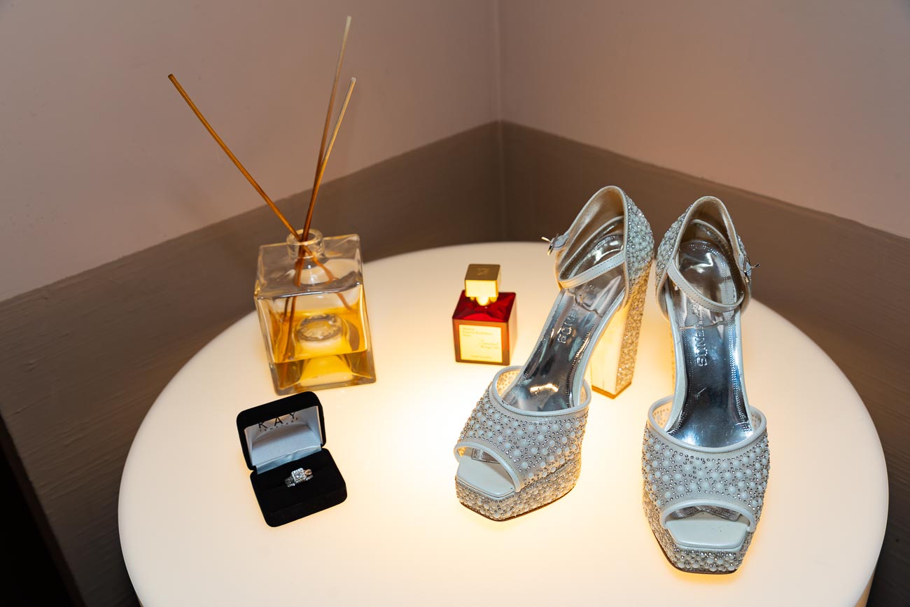 The shoes of the wedding bride photographed on a table together with other wedding details