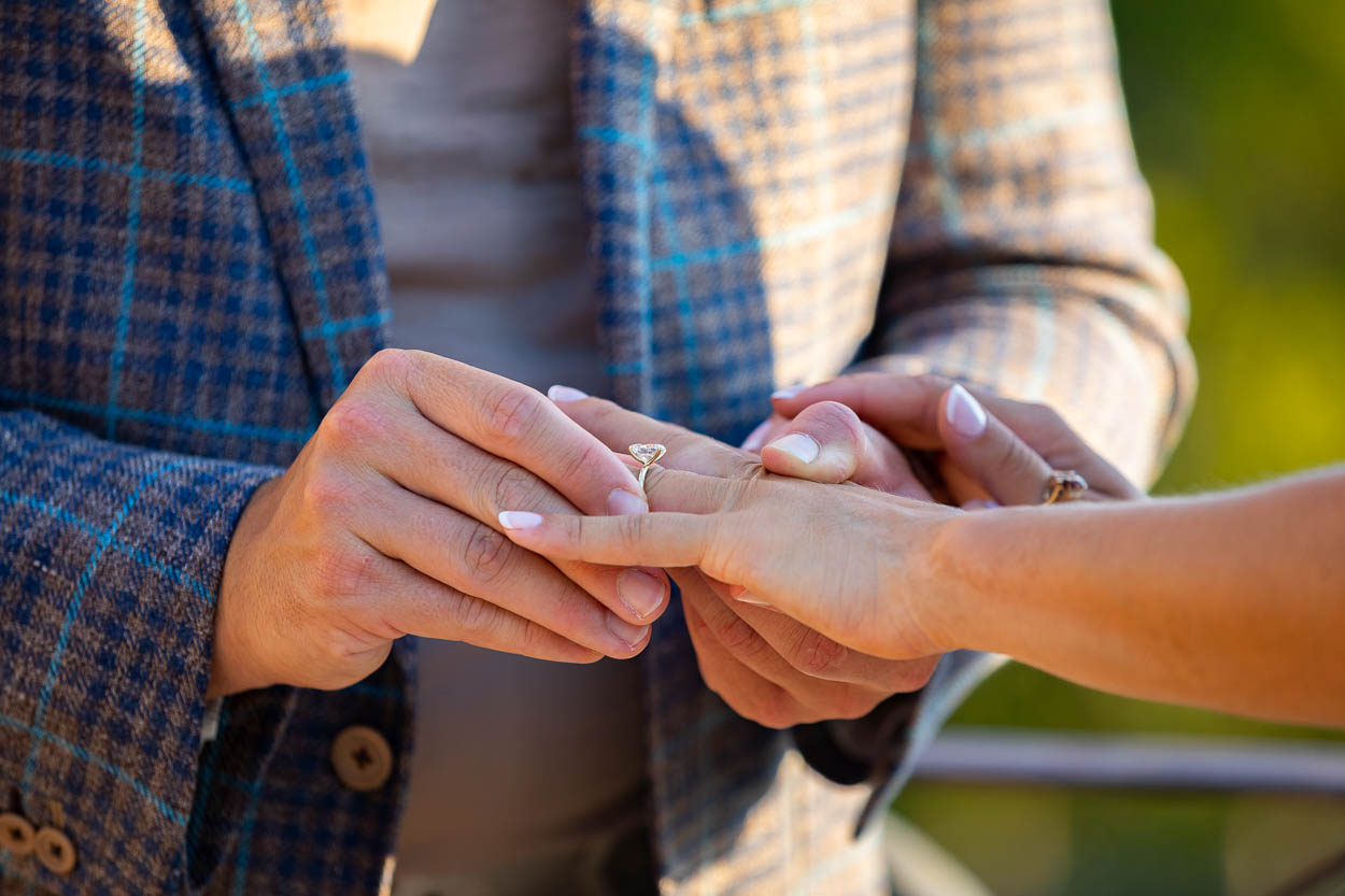 Close up image of the engagement ring photographed as it is being placed on the fiancée's hand finger 