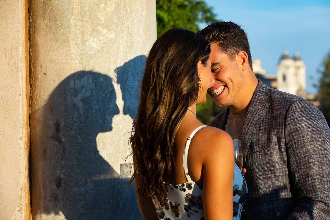 In Love together in Italy during a fun and romantic couple photography session. Smiling image with shadows on an ancient roman column