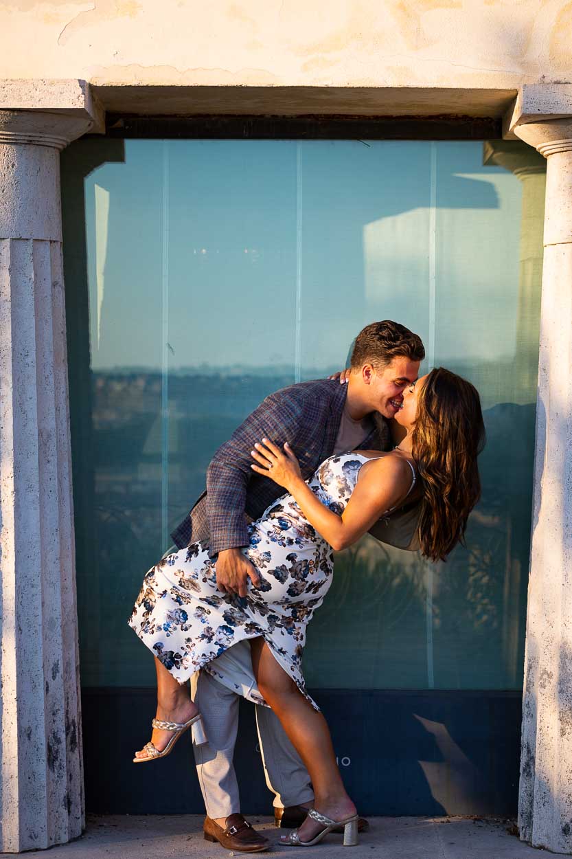 Couple posing for the photo camera with a romantic dip in between columns at sunset