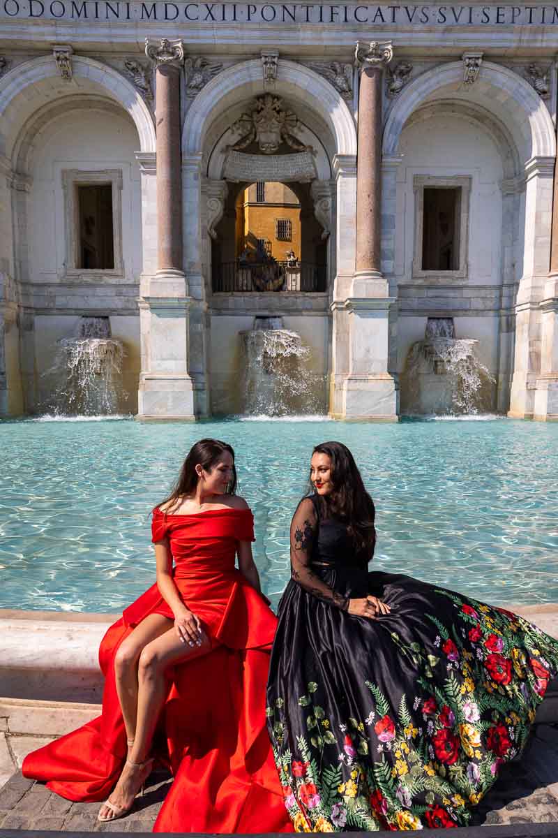 Two models together photographed by the border of a water fountain 
