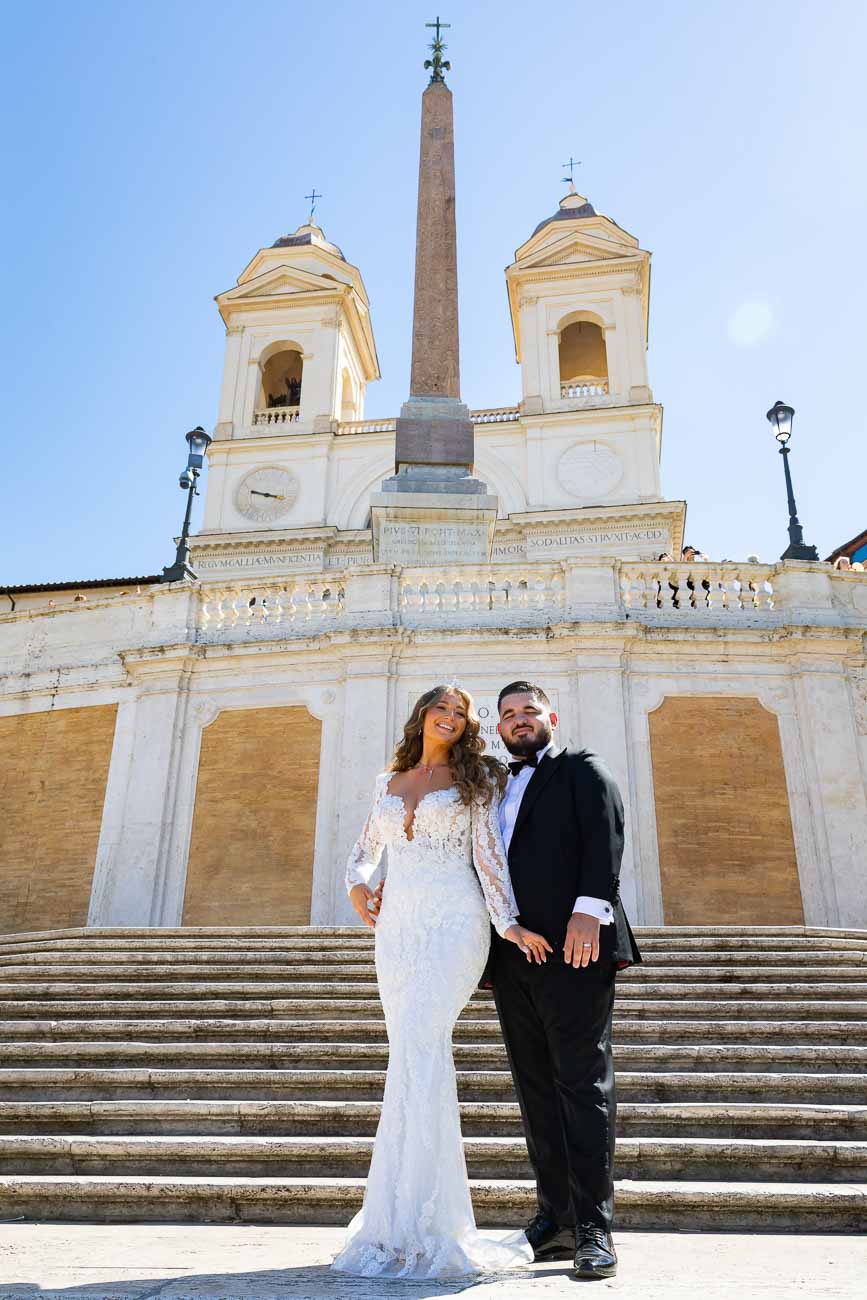 Newlyweds posing for a wedding photo on the Spanish steps in Rome Italy with Church Trinità dei Monti in the background