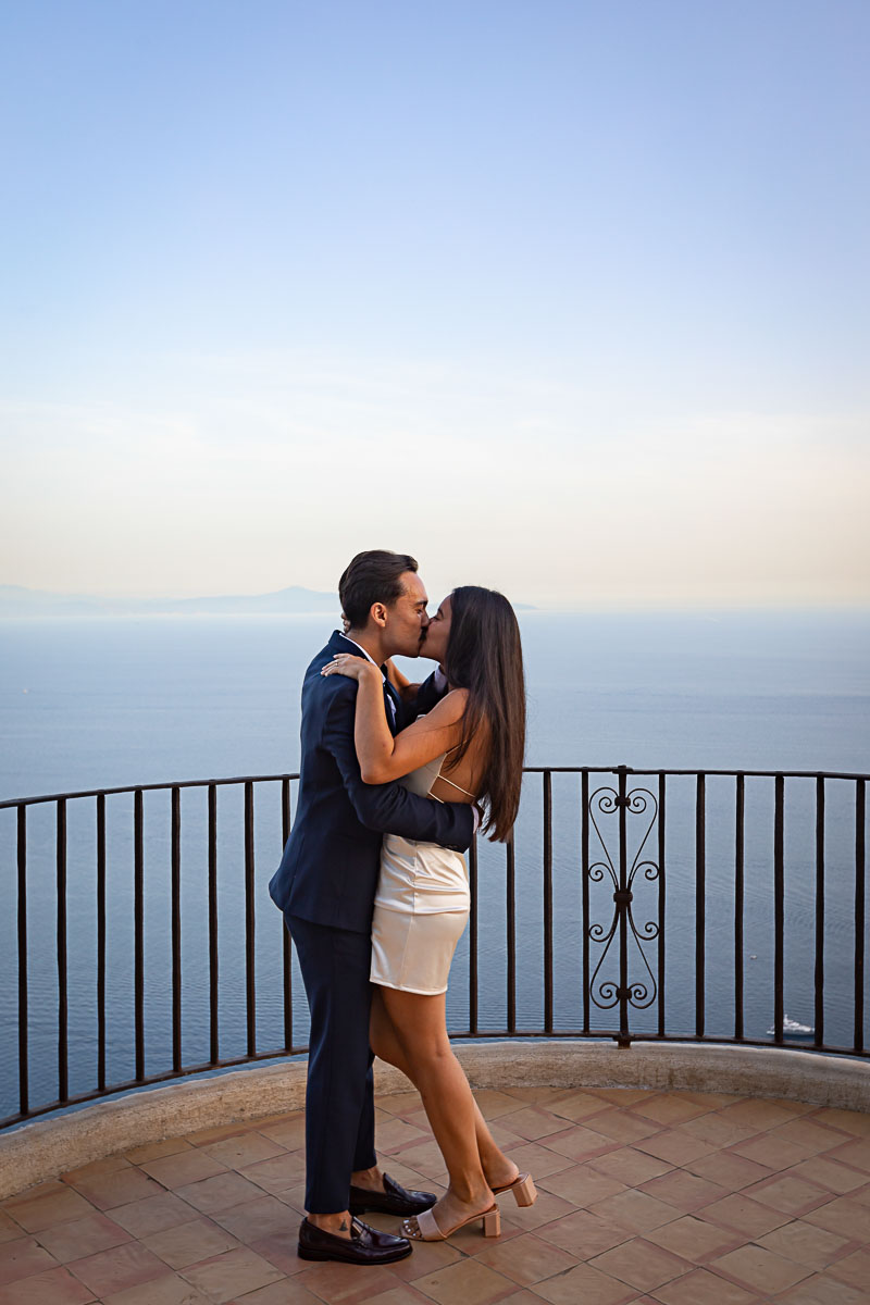 Couple kissing on a terrace overlooking the sea of the Amalfi coast at sundown