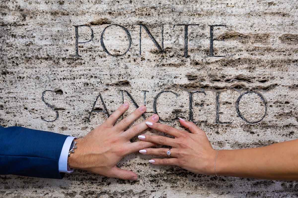 Composed picture of the engagement ring photographed on the hand over the sign of Ponte S Angelo