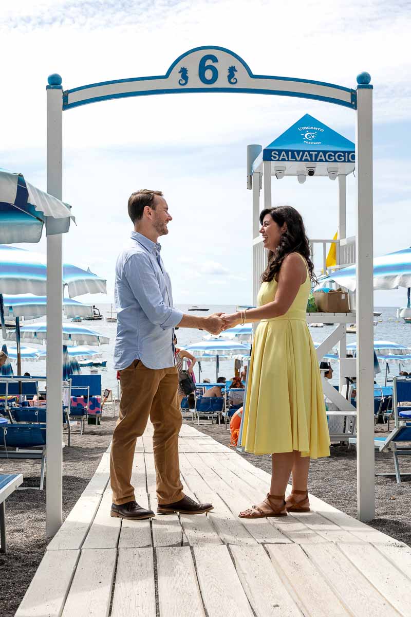 Couple holding hands on the beach boardwalk leading to the Amalfi coast sea